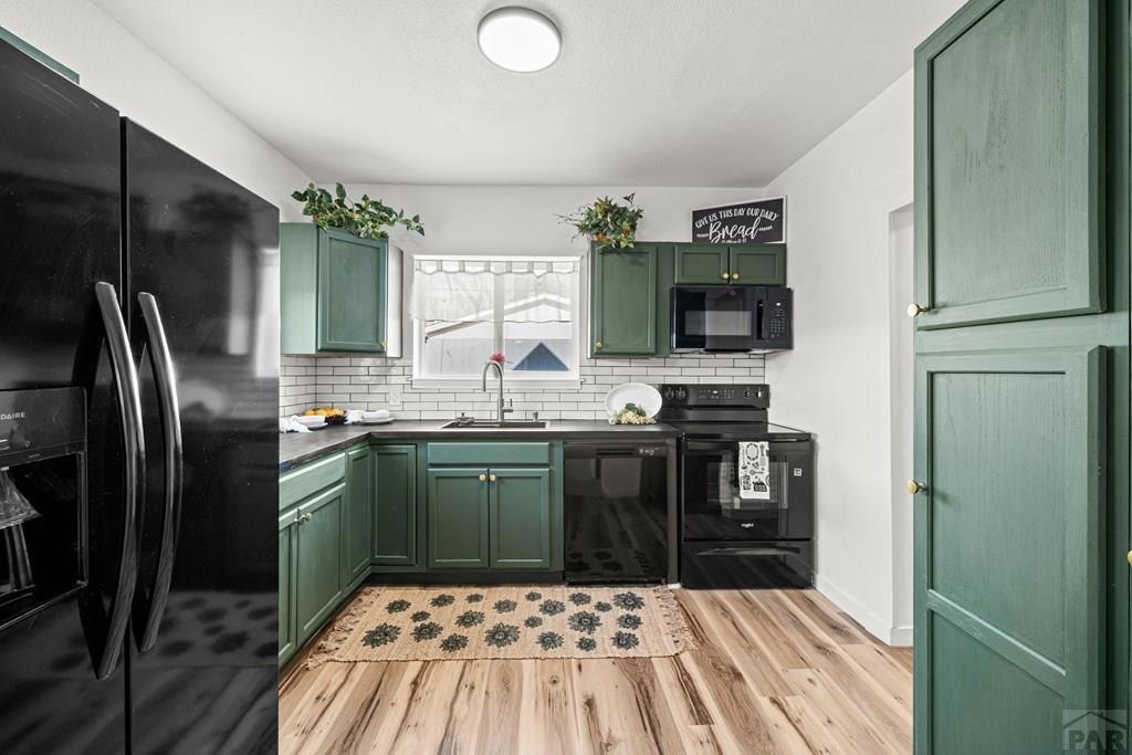 Remodeled kitchen with green cabinets and subway tile